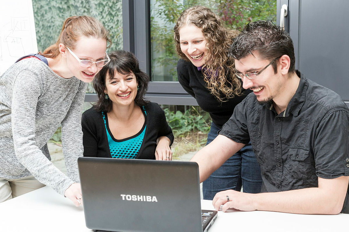 Studierende am Tisch vor einem Laptop sitzend 