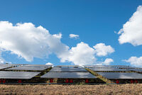 Solarpanele auf einer Wiese unter blauem Himmel mit weißen Wolken