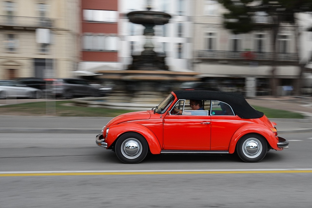 Foto eines fahrenden roten VW Beetle