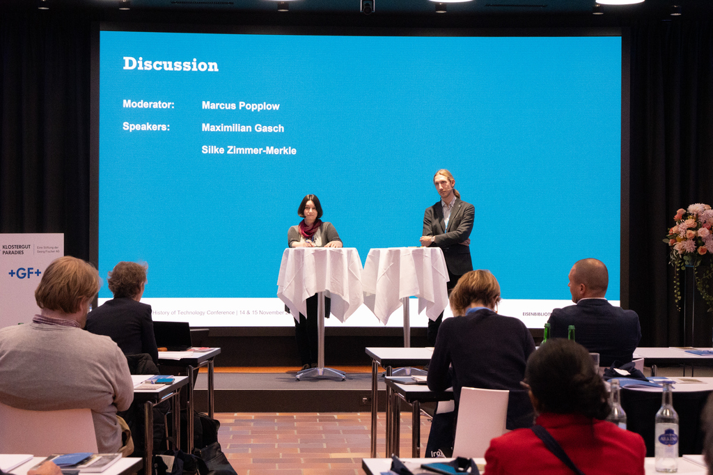 Das Foto zeigt Silke Zimmer-Merkle und Maximilian Gasch am Rednerpult bei der Tagung der Eisenbibliothek in Schaffhausen 2025